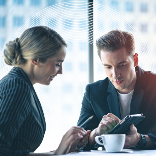 a man and woman looking on mobile phones whilst drinking coffee