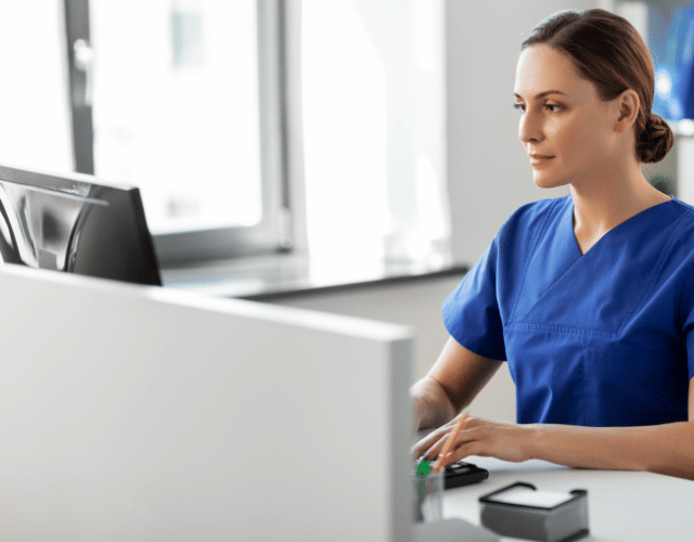 Female nurse sat on desk using computer