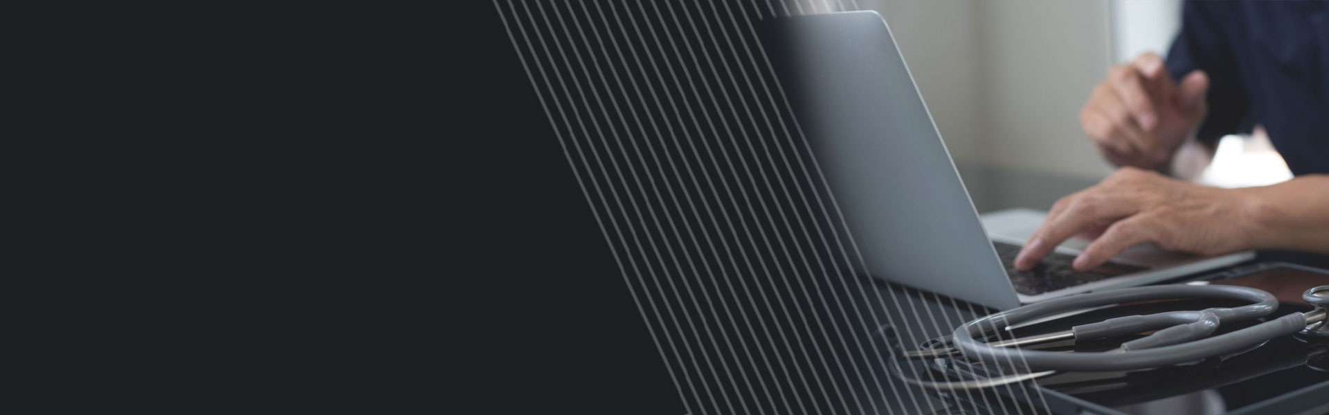 Close up shot of medical professional on a laptop; medical equipment in foreground.