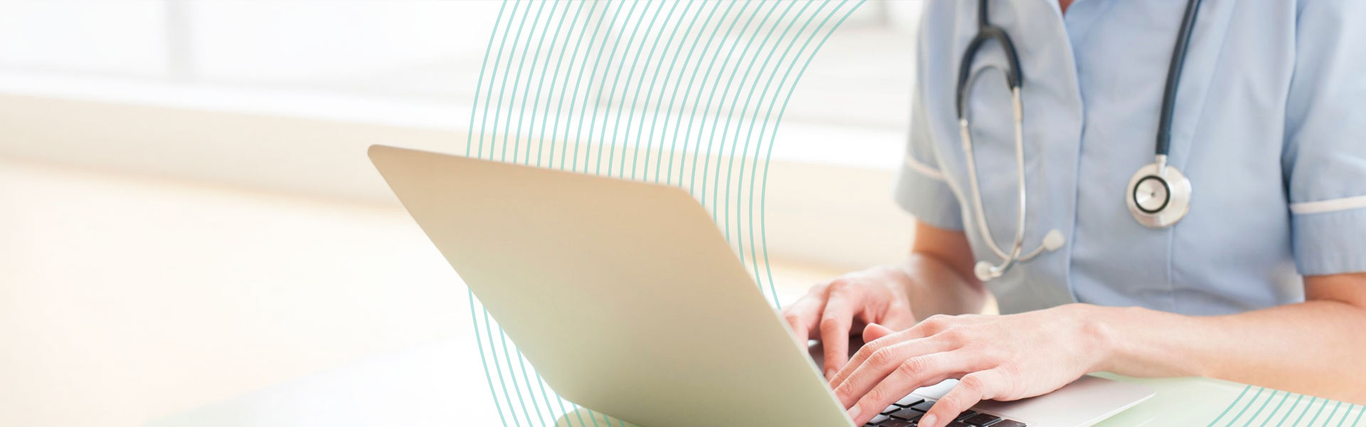 A clinical nurse sitting at a desk and working on a laptop.