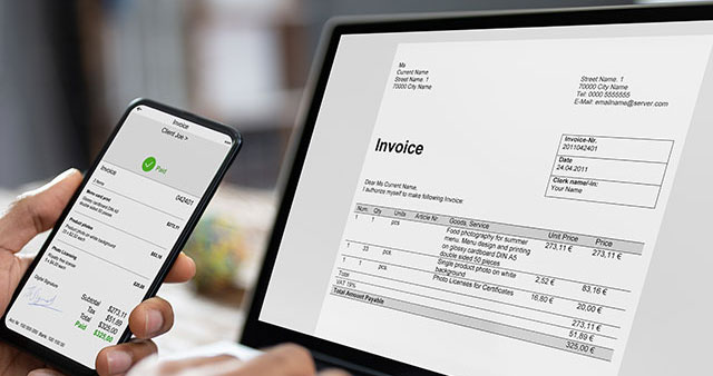 Businessman's Hands Working On Invoice On Laptop