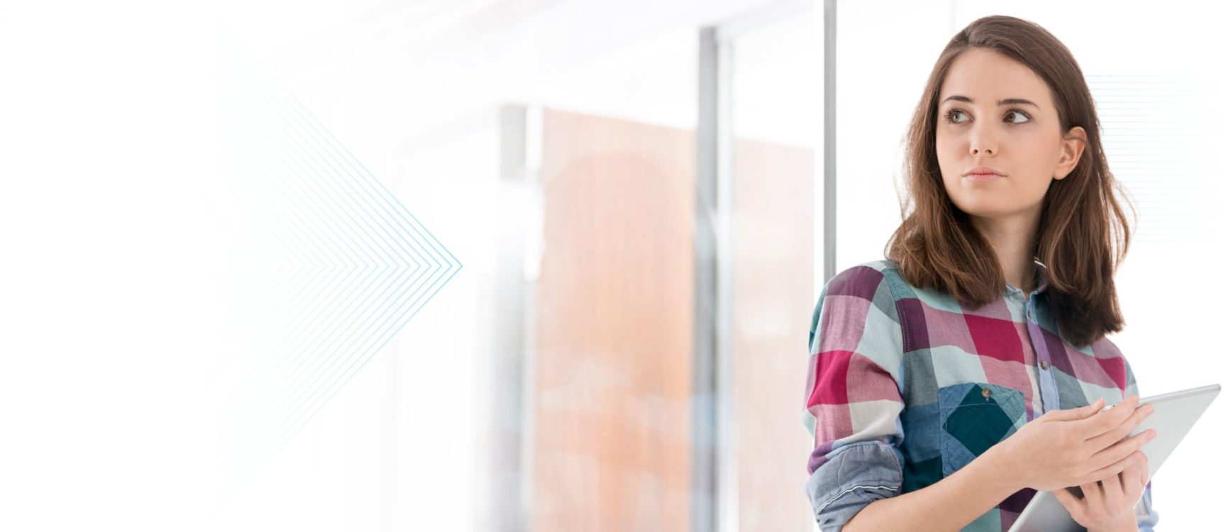 a women in checkered shirt smiling while looking at weekly payrolls on a computer tablet