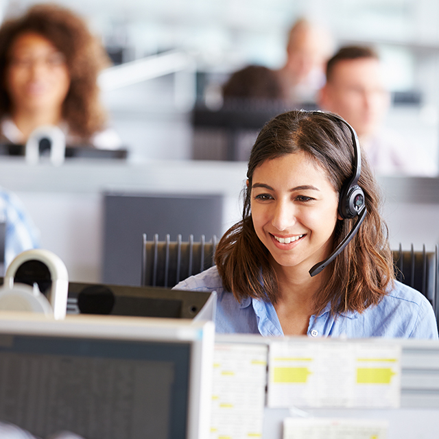 registration-authority services for the NHS. A woman wearing a headset in an office working on a computer