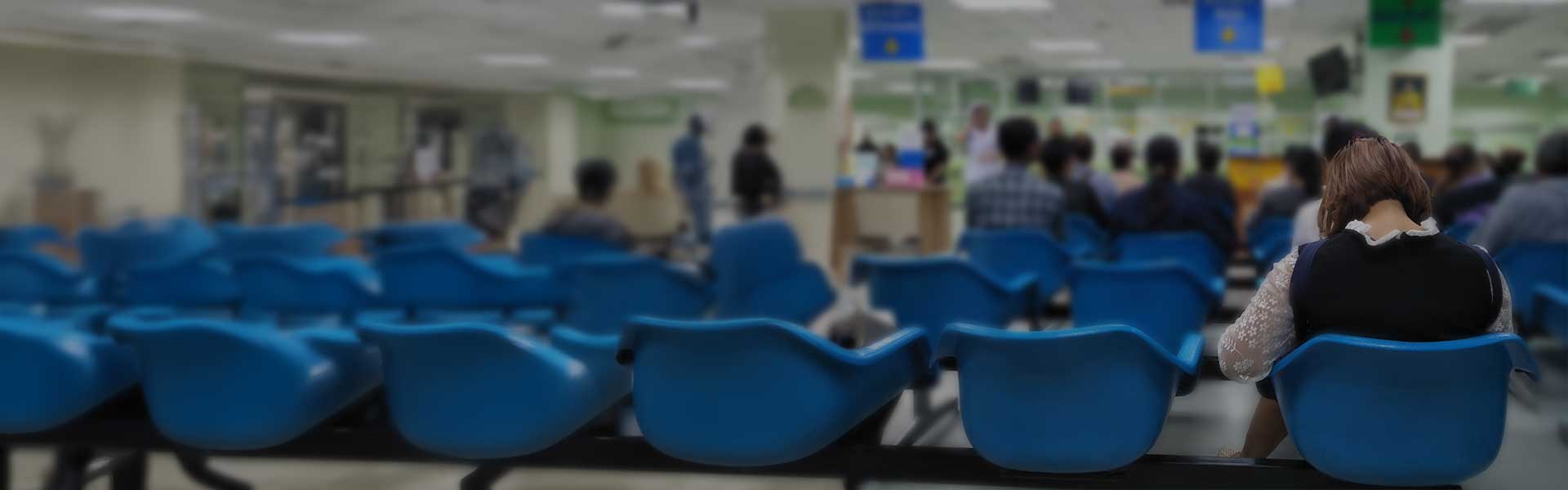young woman sit on blue chair at front the emergency room and many people waiting medical and health services to the hospital,patients waiting treatment at the hospital,blurred image of people